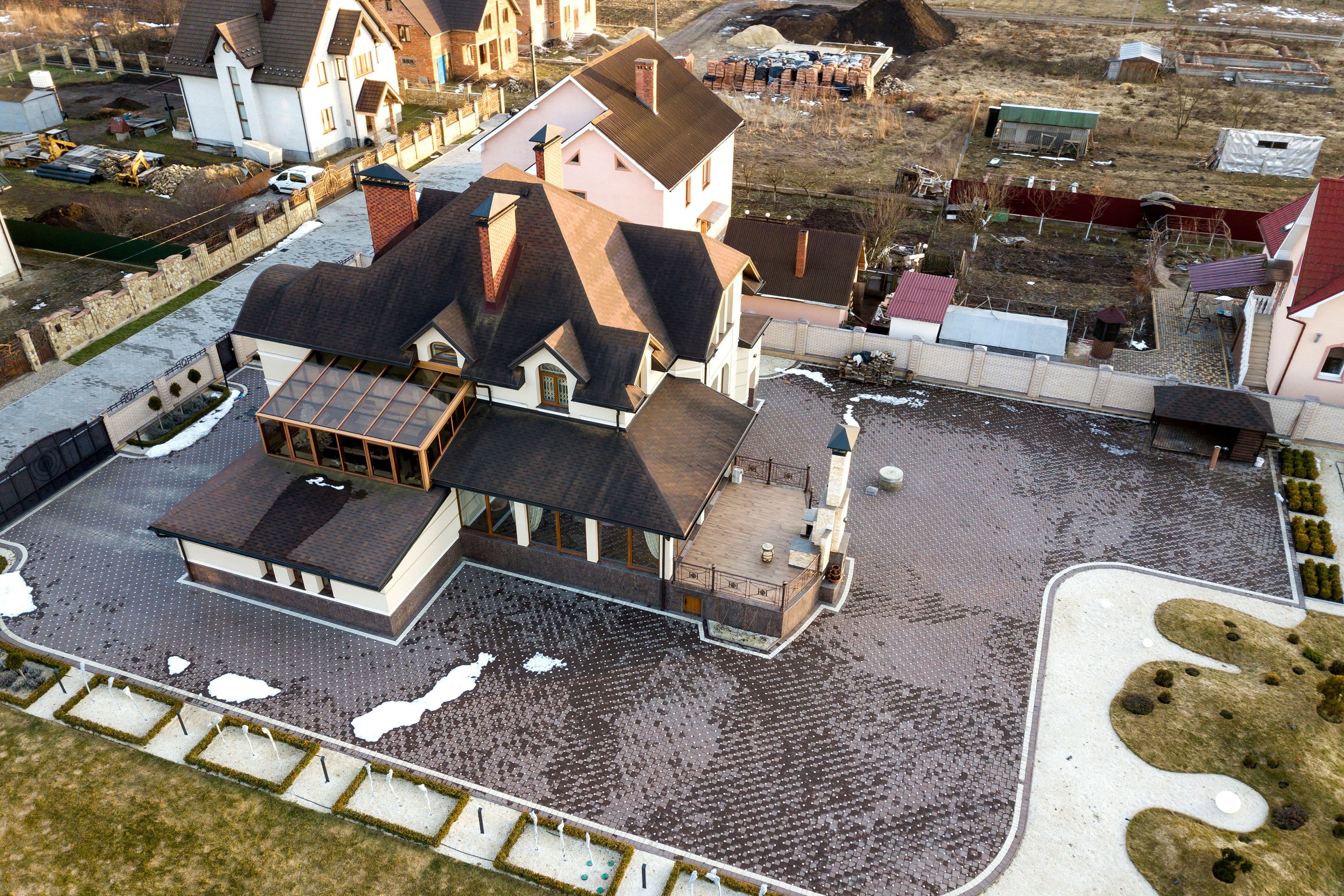 Aerial top view of new residential house cottage with shingle roof on fenced big yard on sunny day.