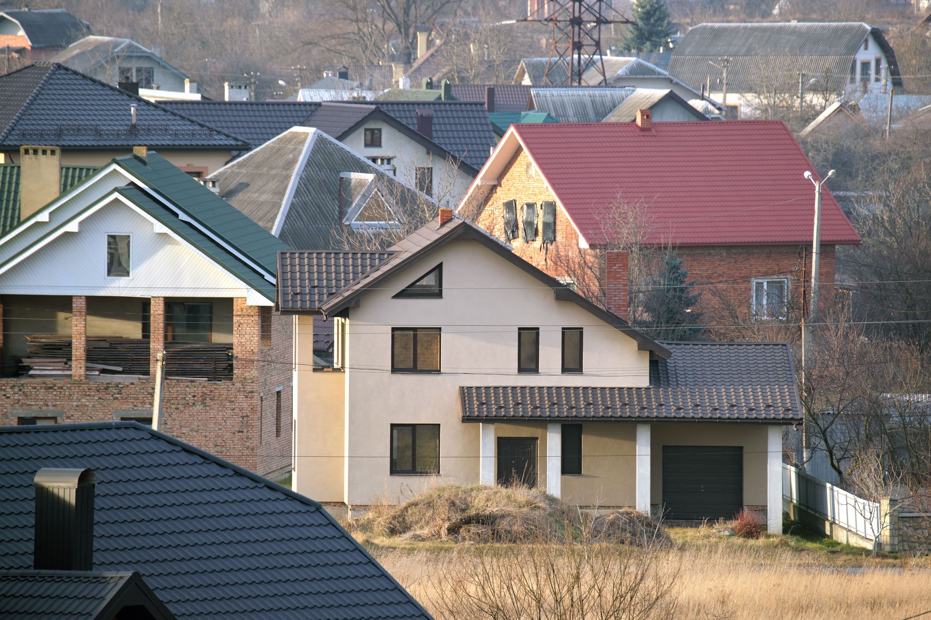 Residential houses with roof tops covered with metallic and ceramic shingles in rural suburban area